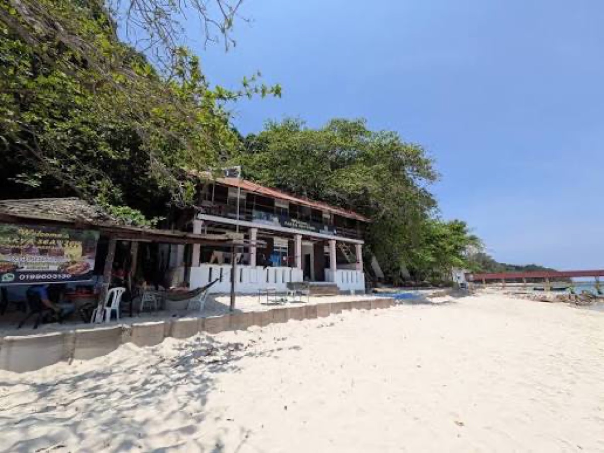 The white two-storey Pak Ya Seaview building on the sand, with its open-fronted cafe and a welcome banner facing the beach.